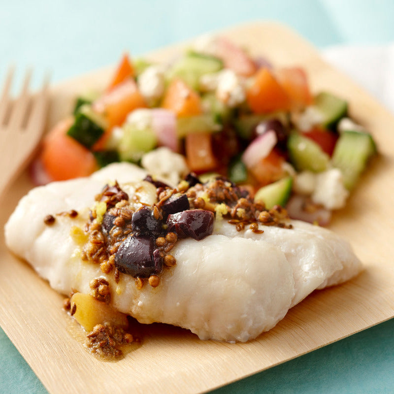 Plated dish of fish with a side salad on a light blue background
